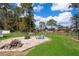 Backyard area with fire pit, lounge chair, grass, and surrounded by trees at 12009 Eagle Point Ct, Leesburg, FL 34788