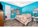 Bedroom with colorful floral bedding, wood-look laminate floors, and painted in bright blue at 12009 Eagle Point Ct, Leesburg, FL 34788
