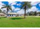 Beautiful single-story home with a lush green lawn and mature palm trees in the front yard at 12009 Eagle Point Ct, Leesburg, FL 34788