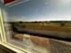 A window view features a large, fenced yard with lush grass extending to neighboring homes under a bright blue sky at 2655 Great Heron Ave, Saint Cloud, FL 34773