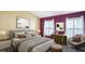 Staged bedroom with painting, many pillows and blankets, soft chair, and two windows at 5825 Princess Caroline Pl, Leesburg, FL 34748