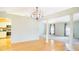 Open dining room with columns, hardwood floors, chandelier, and views to the living room and kitchen at 5825 Princess Caroline Pl, Leesburg, FL 34748