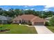 Charming single-story home features a lush lawn, manicured landscaping, and a screened two-car garage at 5825 Princess Caroline Pl, Leesburg, FL 34748