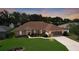 Charming single-story home featuring a well-manicured lawn and a screened two-car garage at dusk at 5825 Princess Caroline Pl, Leesburg, FL 34748