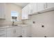 Laundry room with white cabinets, stone countertops, stainless sink, and a window providing natural light at 1020 W Princeton St, Orlando, FL 32804