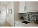 Elegant wet bar with a gray tile backsplash and white countertop and cabinetry, plus stainless steel bar accessories at 1020 W Princeton St, Orlando, FL 32804