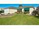 Cream-colored home featuring a well-manicured lawn, tasteful landscaping, and green awnings over the windows at 3049 Glenwood Pl, The Villages, FL 32162