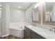 Elegant bathroom with dual sinks, vanity with marble counters, soaking tub, and glass-enclosed shower at 1928 Michigan Ct, Kissimmee, FL 34759