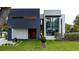 Modern home with a contrasting dark and white exterior, featuring an elegant wood door and lush green landscaping at 2522 Lafayette Ave, Winter Park, FL 32789