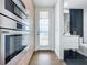 Hallway with built-in ovens, white door, and a peek into a modern half bathroom at 2522 Lafayette Ave, Winter Park, FL 32789