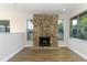 Bright and airy living room with a stone fireplace, large windows and wood-look floors at 666 Sausalito Blvd, Casselberry, FL 32707