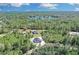 Aerial view of a modern home with a dark roof surrounded by lush trees, with a lake visible in the background at 30 Fisher Trail, Ocklawaha, FL 32179