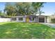 Beautiful single-story house with a yellow door and a garage, surrounded by lush trees at 3703 Pembrook Dr, Orlando, FL 32810