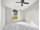 Bright bedroom with large arched window, white tile flooring, and ceiling fan at 5418 S Bracken Ct, Winter Park, FL 32792