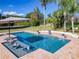 Inviting pool area with in-pool seating, gentle waterfalls, and a relaxing patio with a large umbrella at 10542 Wittenberg Way, Orlando, FL 32832