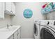 Functional laundry room with white cabinetry, modern washer and dryer, and decorative signage at 14132 Murcott Blossom Blvd, Winter Garden, FL 34787
