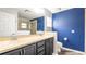 Bathroom with dual sinks, dark wood cabinets, large mirror, stand up shower and blue accent wall at 4245 Arlington Ridge Blvd, Leesburg, FL 34748