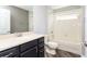 Bathroom with dark vanity, mirror, toilet and tiled shower over tub at 4245 Arlington Ridge Blvd, Leesburg, FL 34748