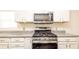 Up close shot of the stainless gas range and microwave with white cabinets and granite countertops at 4245 Arlington Ridge Blvd, Leesburg, FL 34748