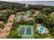 Aerial view showcasing tennis courts, a pool, and residential buildings surrounded by lush greenery at 120 Hibiscus Woods Ct # 8D, Deltona, FL 32725