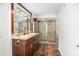 Well-lit bathroom with double sink vanity and glass-enclosed shower at 8984 Houston Pl # 103, Orlando, FL 32819