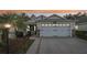 House exterior at dusk with a white garage door and landscaping at 2584 Dividing Creek Path, The Villages, FL 32162