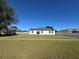 Spacious backyard with a modern white house featuring three doors that lead to an open green lawn at 6208 Sw 129Th St, Ocala, FL 34473