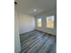Bright bedroom with gray wood flooring, two windows, white walls, and an air conditioning unit at 6208 Sw 129Th St, Ocala, FL 34473