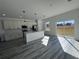 Modern kitchen with gray wood flooring, white cabinets, stainless steel appliances, kitchen island, and sliding glass doors at 6208 Sw 129Th St, Ocala, FL 34473