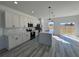 Modern kitchen with gray wood flooring, white cabinets, stainless steel appliances, kitchen island and stylish pendant lighting at 6208 Sw 129Th St, Ocala, FL 34473