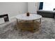 Close-up of a living room with a marble topped coffee table on a plush gray rug and a view of the doorway at 476 Banyon Tree Cir # 104, Maitland, FL 32751