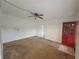 Spacious living room with a red front door, neutral carpet, and a ceiling fan at 919 Timor Ave, Orlando, FL 32804