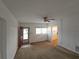 Bright living room featuring a ceiling fan, neutral carpet, and a front door with a red frame at 919 Timor Ave, Orlando, FL 32804