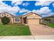 Tan house with red shutters, paver driveway, and landscaped lawn at 10063 Malmsbury Rd, Orlando, FL 32829