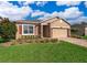 Tan house with red shutters, paver driveway, and landscaped lawn at 10063 Malmsbury Rd, Orlando, FL 32829