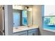Bathroom featuring a double sink vanity, a large mirror, and a window with a view of the outdoors at 1173 Basalt Ln, Sanford, FL 32771
