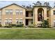 Two-story apartment building with neutral stucco, arched entryway, landscaped lawn, and visible windows at 2878 Club Cortile Cir # A, Kissimmee, FL 34746