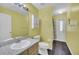 Bright bathroom with a speckled granite countertop, white cabinets, and yellow wall at 2204 Clementine Trl, Clermont, FL 34714