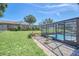 Backyard view showcasing the pool and its screened enclosure, surrounded by a well-maintained lawn at 2204 Clementine Trl, Clermont, FL 34714