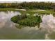 Aerial view of the island in the lake, showcasing the lush greenery, walking path, and sand at 1055 Lake Berkley Dr, Kissimmee, FL 34746
