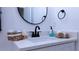 Bathroom vanity featuring a modern round mirror, sleek black faucet, and decoratively arranged towels at 13882 Sw 56Th Ln, Ocala, FL 34482