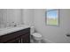Half bathroom with dark vanity cabinet, gray granite countertop, and a window at 7247 Rolling Leaf Rd, Groveland, FL 34736