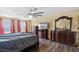 Bedroom featuring a large bed, wood floors, and dark wood dressers with a ceiling fan for comfortable living at 1911 Betsy Ross Ln, St Cloud, FL 34769