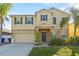 Two-story home featuring manicured landscaping and a welcoming front entrance with an attached two car garage at 1911 Betsy Ross Ln, St Cloud, FL 34769