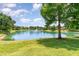 Scenic pond view, with well maintained green grass, trees, and a fountain at 2523 Madron Ct, Orlando, FL 32806