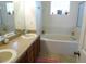Bathroom with double sinks, wood cabinets, large mirror, and separate bathtub at 721 Willow Run St, Minneola, FL 34715