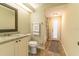 A neutral colored bathroom featuring a marble counter, cabinets, toilet and gray runner rug on tiled floor at 4916 Fiji Cir # 11, Orlando, FL 32808