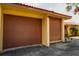 Attached garage with brown overhead door and yellow exterior walls at 4916 Fiji Cir # 11, Orlando, FL 32808