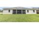 Rear view of the home featuring a screened-in lanai, solar panels, and a well-maintained lawn at 1518 Alligator St, St Cloud, FL 34771