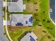 Aerial view of a gray home with solar panels, situated on a well-manicured lawn near a pond at 11357 Satire St, Orlando, FL 32832